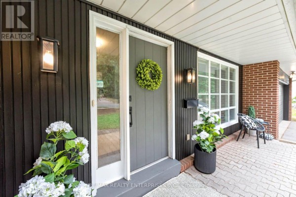 Close-up of a front door with a gray door, wreath, brick exterior, and windows. - 829 Terlin Boulevard, Mississauga