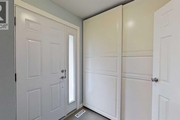 Interior entrance with white door, sidelight, and tall white storage cabinets. - 83, 1055 72 Avenue Nw, Calgary