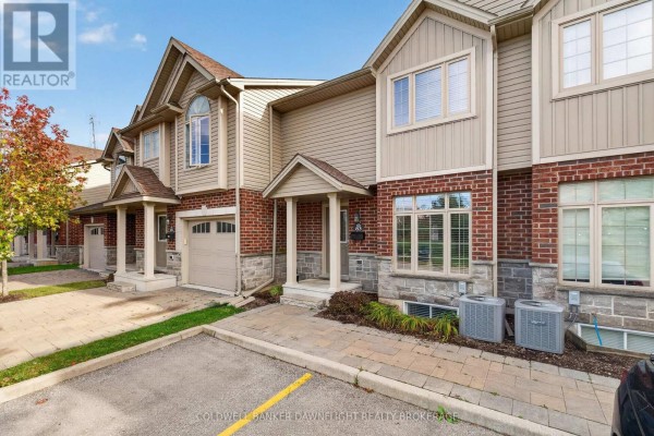 Side view of townhouses showing beige siding, brick details, and air conditioning units outside. - 83 - 1061 Eagletrace Drive, London North