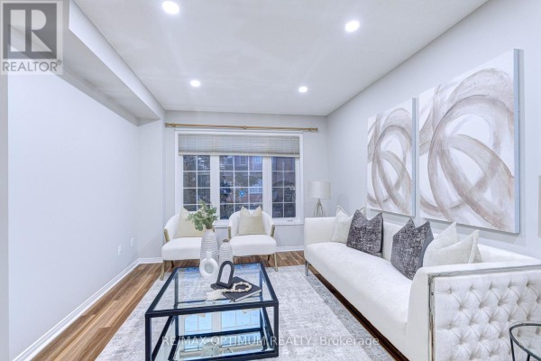 Living room with light grey walls, wood floors, a sofa, chairs, and a large window. - 83 - 5030 Heatherleigh Avenue, Mississauga