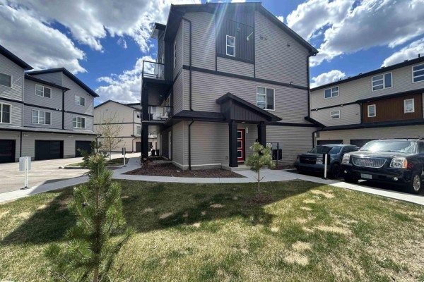 Side view of townhouse featuring a red front door and landscaped pathway. - #83 1203 163 St Sw, Edmonton