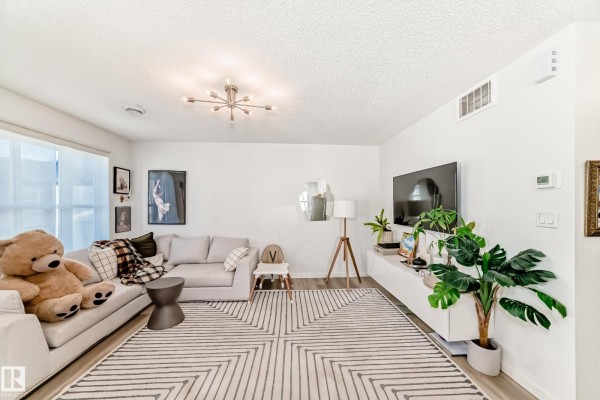Bright kitchen with stainless steel appliances, white cabinetry, and a view of the hallway. - #83 1203 163 St Sw, Edmonton