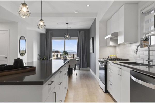 Kitchen island and sink with view of dining area and balcony with mountain scenery. - 83 7381 Preston Boulevard, Mission