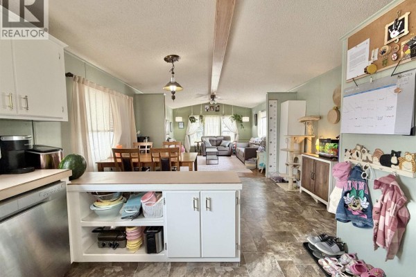 View from the kitchen showing the dining area and living room with furniture. - 83 770 N Eleventh Avenue, Williams Lake