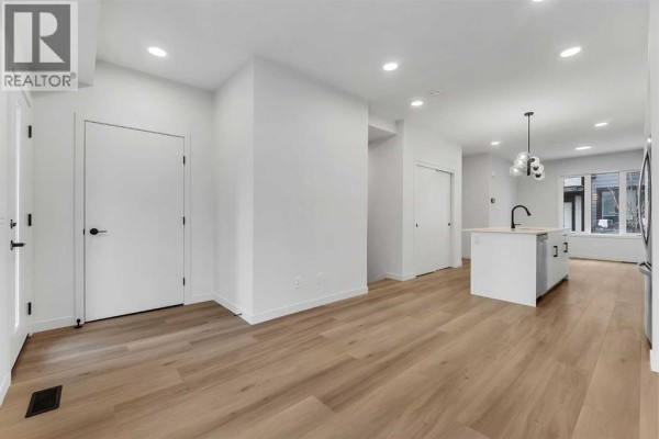 Open concept living space showing a white kitchen island and light wood floors. - 83 Arbour Lake Court Nw, Calgary