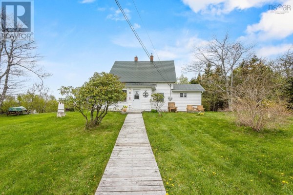 Wooden boardwalk leading to the front entrance of a white house with a green roof and surrounding grass. - 83 Baker Road, Myers Point