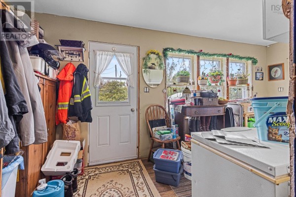 Interior view of a mudroom with coats, boots, storage bins, and a door with a window. - 83 Baker Road, Myers Point