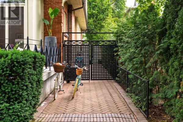 Outdoor patio with modern grey seating, potted plants, and a view of lush greenery. - 83 Binscarth Road, Toronto