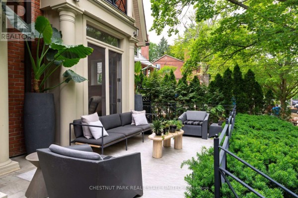 Front entrance of a red brick house with a glass door, stone steps, and classical columns. - 83 Binscarth Road, Toronto