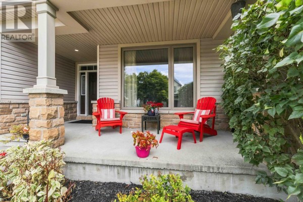 Covered front porch with two red adirondack chairs, a small table, and potted plants. - 83 Blackshire Circle, Ottawa