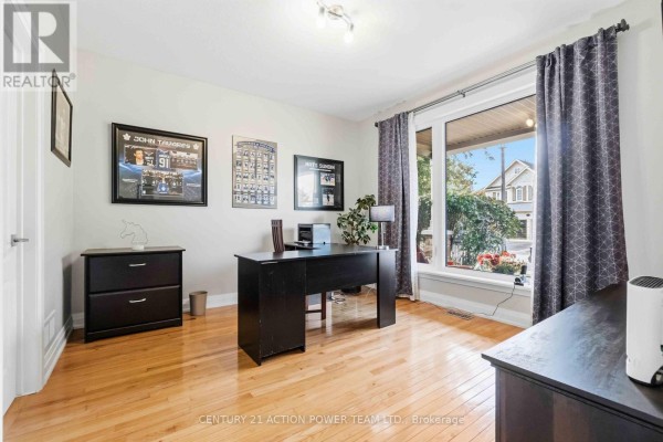 Home office with a large window, wooden floor, desk, chair, and framed pictures on the wall. - 83 Blackshire Circle, Ottawa