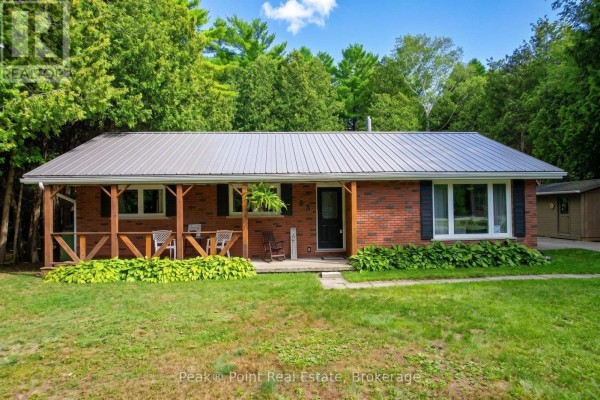 Front view of a red brick bungalow with a wood porch and metal roof. - 83 Boulton Street, South Bruce Peninsula