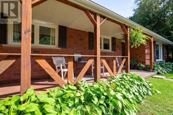Close-up of the wooden porch with chairs and railings against the brick exterior. - 83 Boulton Street, South Bruce Peninsula