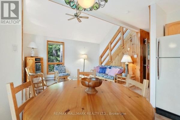 Dining area with wooden table, chairs, and living room with rattan furniture. - 83 Chapel Road, Madawaska Valley