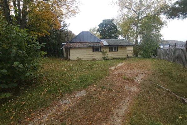 A long, single-story yellow cottage with a metal roof is surrounded by dry grass. - 83 Fell Rd, R.r. #2 Baptiste, Hastings Highlands