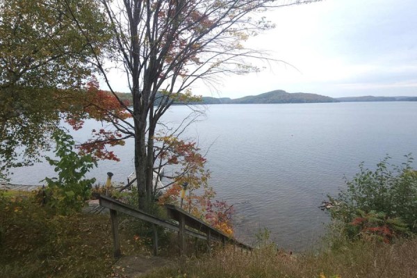 Wooden stairs descend a grassy slope towards a wide lake with hills in the distance. - 83 Fell Rd, R.r. #2 Baptiste, Hastings Highlands