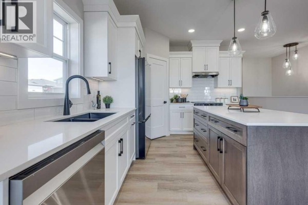 View of the kitchen, showing white cabinets, dark faucet, quartz countertops, and a large island. - 83 Gray Close, Sylvan Lake