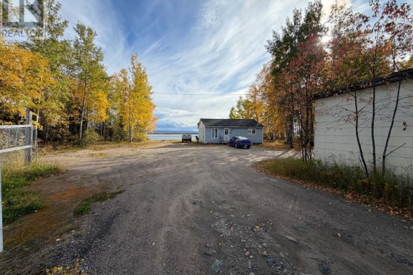 Gravel driveway leads past commercial buildings towards a house and Goose Bay in the distance. - 83 Hamiltion River Road, Happy Valley   Goose Bay
