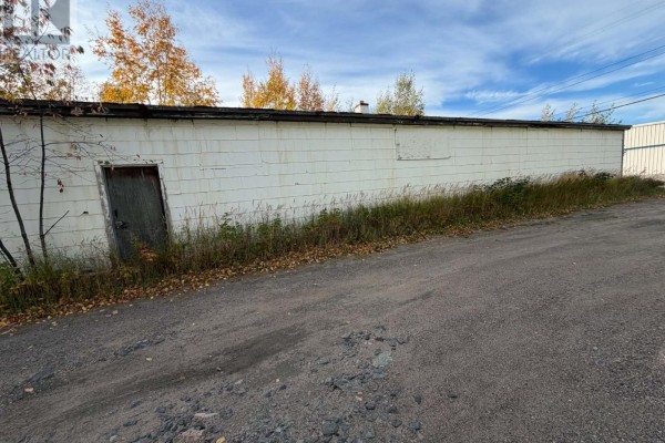 Long white commercial building with a weathered wooden door on the left side. - 83 Hamiltion River Road, Happy Valley   Goose Bay