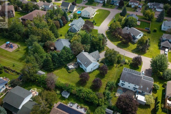Aerial view of a large residential house surrounded by green trees and other homes. - 83 Kennedy Drive, Charlottetown