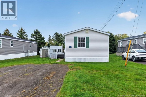 Side view of a single-family home with light grey siding, green shutters, and a dark grey roof. - 83 Louisbourg Street, Shediac