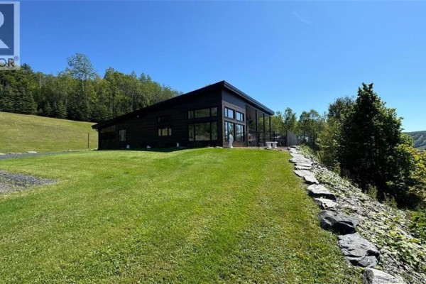 Bright living room with large windows, recliner chair, and scenic views. - 83 Maxime Road, Saint Jacques