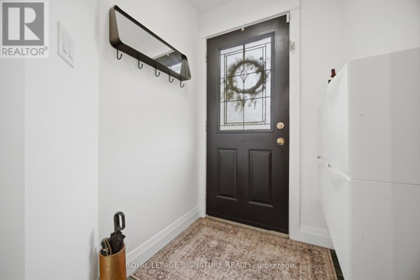 Interior view of a small entryway with a dark door, mirror, and storage cabinet. - 83 Mill Street S, Brampton