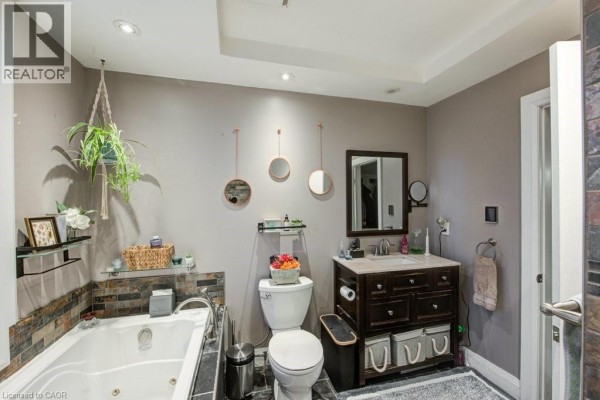 Living area with a vaulted ceiling, a stone fireplace, leather sofa, and built-in shelving. - 83 Oxford Street, Woodstock