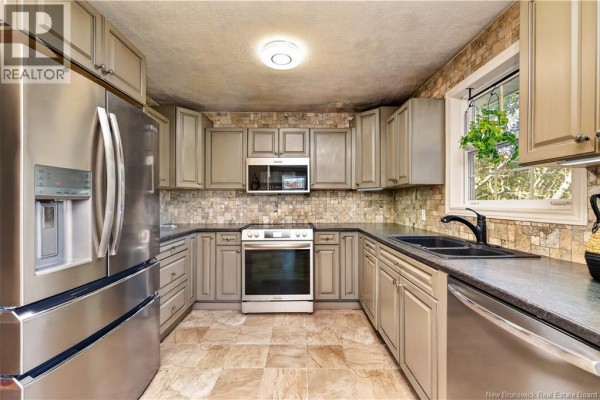 Aerial view showing 83 Renfrew, Petitcodiac, surrounded by trees and near local amenities. - 83 Renfrew, Petitcodiac