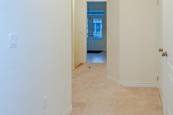 Unfurnished hallway with beige carpet, white walls, and a view towards the front entrance. - 83 Robin Trail, Scugog
