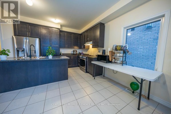Kitchen with dark wood cabinets, stainless steel appliances, tiled floor, and a large window. - 83 Robin Trail, Scugog