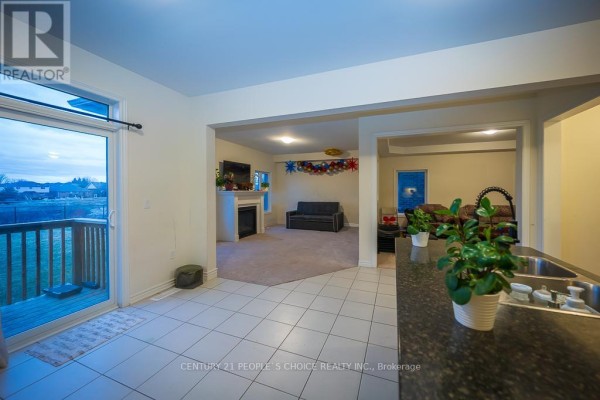 Open-concept living area with a fireplace, carpeted floors, and sliding glass door to a deck. - 83 Robin Trail, Scugog