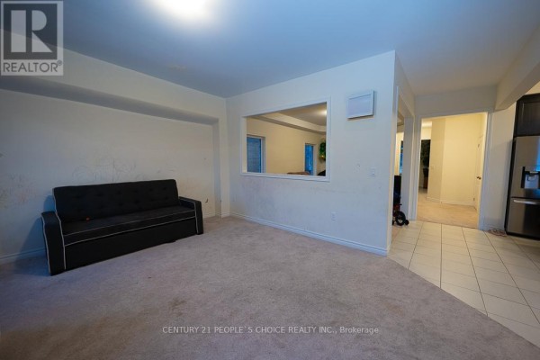 Living room with a dark sofa, beige carpet, and a rectangular cut-out in the wall. - 83 Robin Trail, Scugog