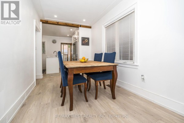 Dining area with a wooden table, four blue chairs, and a window overlooking the exterior. - 83 Scott Road, Toronto