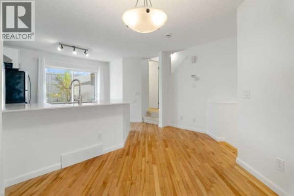 Open concept living and dining area with hardwood floors and a white island. - 83 Tuscany Springs Gardens Nw, Calgary
