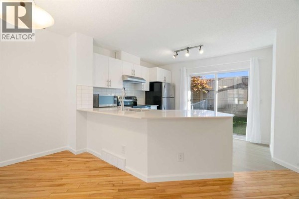 Kitchen with white cabinets, stainless steel appliances, and a large island with a sink. - 83 Tuscany Springs Gardens Nw, Calgary