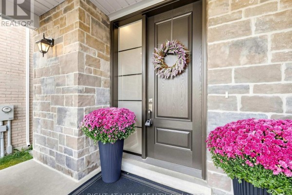 View of the dark wood front door with sidelight, wreath, and potted pink chrysanthemums. - 83 Vasey Road, Bradford West Gwillimbury
