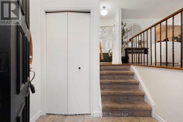 Interior entryway with view of bi-fold doors, carpeted stairs, and railing. - 83 Waverley Road, Clarington