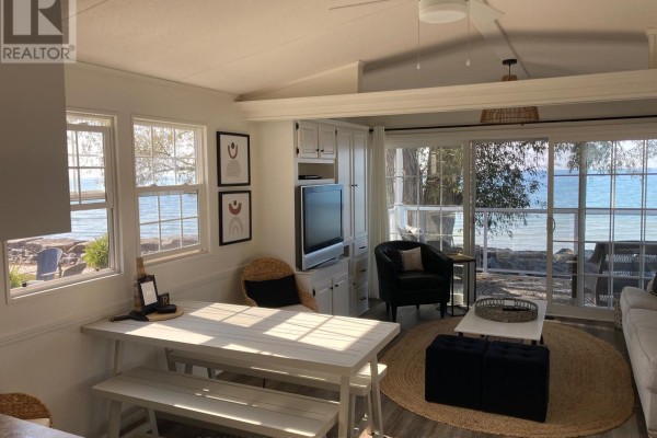 Living area with a dining table, couch, and multiple windows with lake views. - 83 Wyldewood, Port Colborne