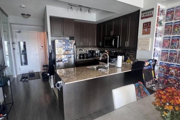 Kitchen area with dark cabinets, granite countertops, and stainless steel appliances. - 830 - 15 James Finlay Way, Toronto