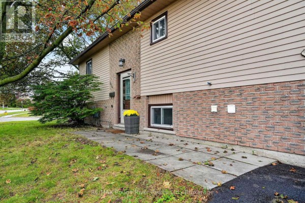 Close-up view of the house entrance with a concrete walkway, beige siding, and brick lower level. - 830 Ewing Court, Cobourg