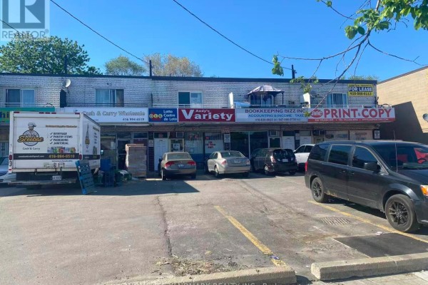 Street view of a strip mall with various businesses, including Andy's Variety, and parked cars. - 830 Wilson Avenue, Toronto