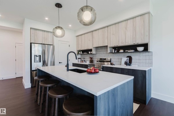 Kitchen island with seating, pendant lights, stainless steel refrigerator, and light wood cabinetry. - 8303 Kiriak Lo Sw, Edmonton
