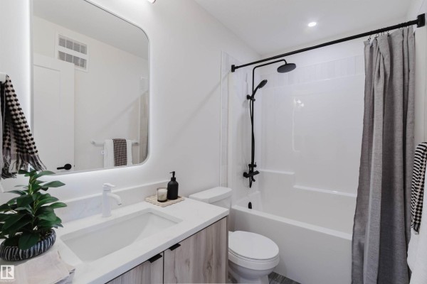 Contemporary bathroom with white tub-shower, vanity, toilet, and black fixtures. - 8303 Kiriak Lo Sw, Edmonton