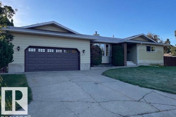 Close-up of the driveway and garage entrance of a light yellow house. - 8305 100 Av, Fort Saskatchewan
