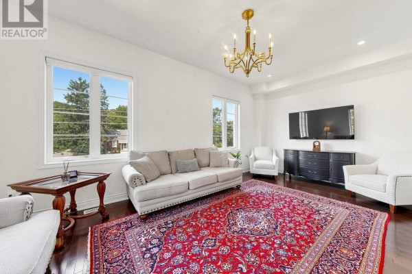 Living room with white walls, large windows, a red patterned rug, dark wood floors, and a gold chandelier. - 8313 Islington Avenue, Vaughan