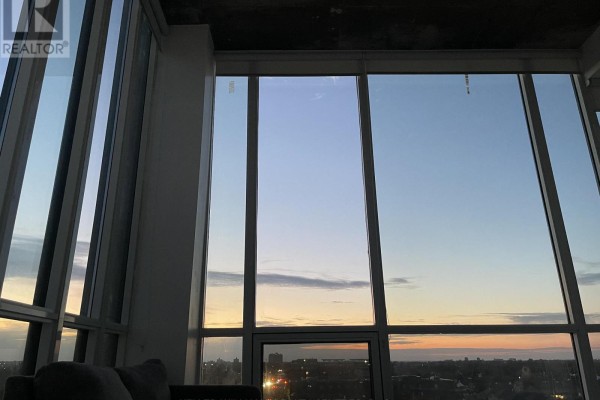 Sunset view from apartment through large windows overlooking a city skyline. - 832 - 1900 Simcoe Street N, Oshawa