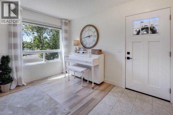 Living room with a sectional sofa, fireplace, television, and large windows overlooking the street. - 8320 Centre Street Ne, Calgary