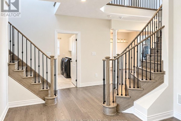 Foyer with a curved staircase featuring grey treads, black balusters, and white walls. - 833 Langford Boulevard, Bradford West Gwillimbury