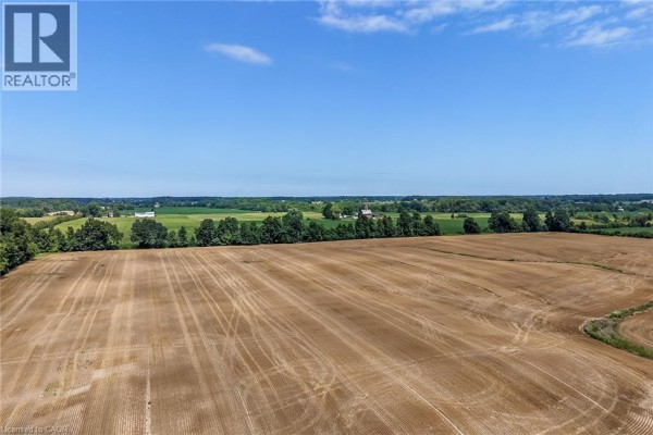 Aerial view of a vast, harvested field with tire tracks and a treeline. - 833 Lynn Valley Road, Port Dover